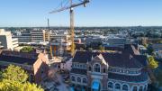 The heritage Jubilee building sits in the foregound, a big crane is in the middle of the site.  Hackett Hall heritage building sits to the left